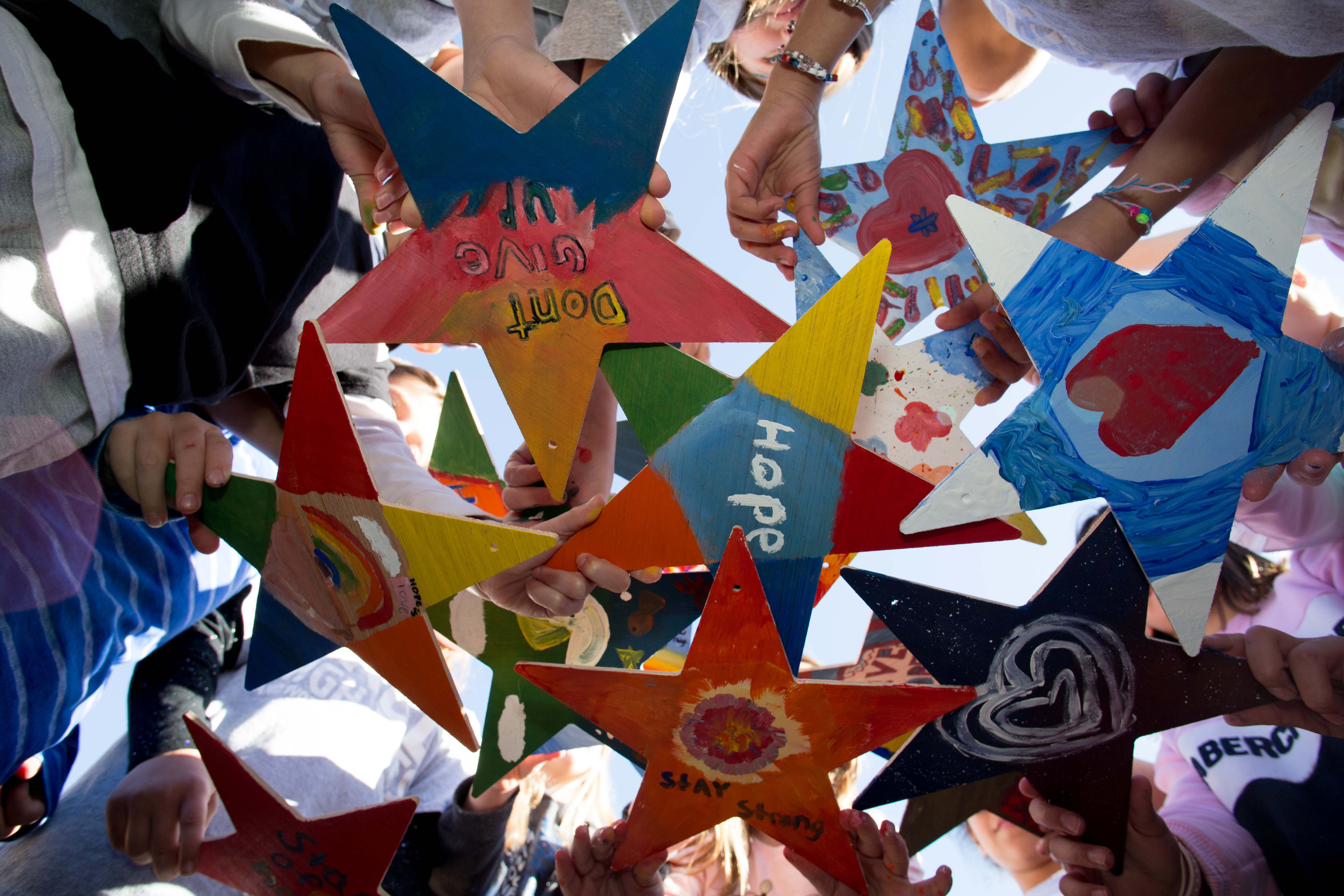 Kids holding painted Stars of HOPE after a school Paint and Process Project