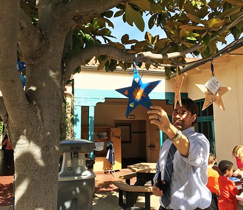 Principal, Dr. Nick Bruski reading the back of a Stars of HOPE hanging in the school courtyard trees after the California Mudslide.